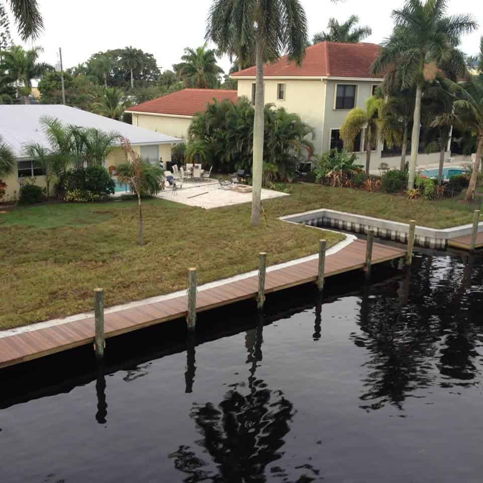Residential canal-front property with a newly constructed curved dock and vinyl seawall.