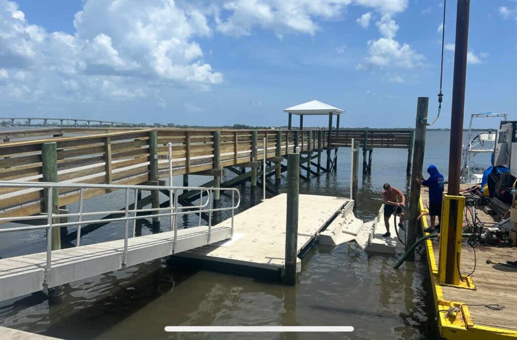 Floating dock with aluminum gangway under construction next to wooden fishing pier with gazebo