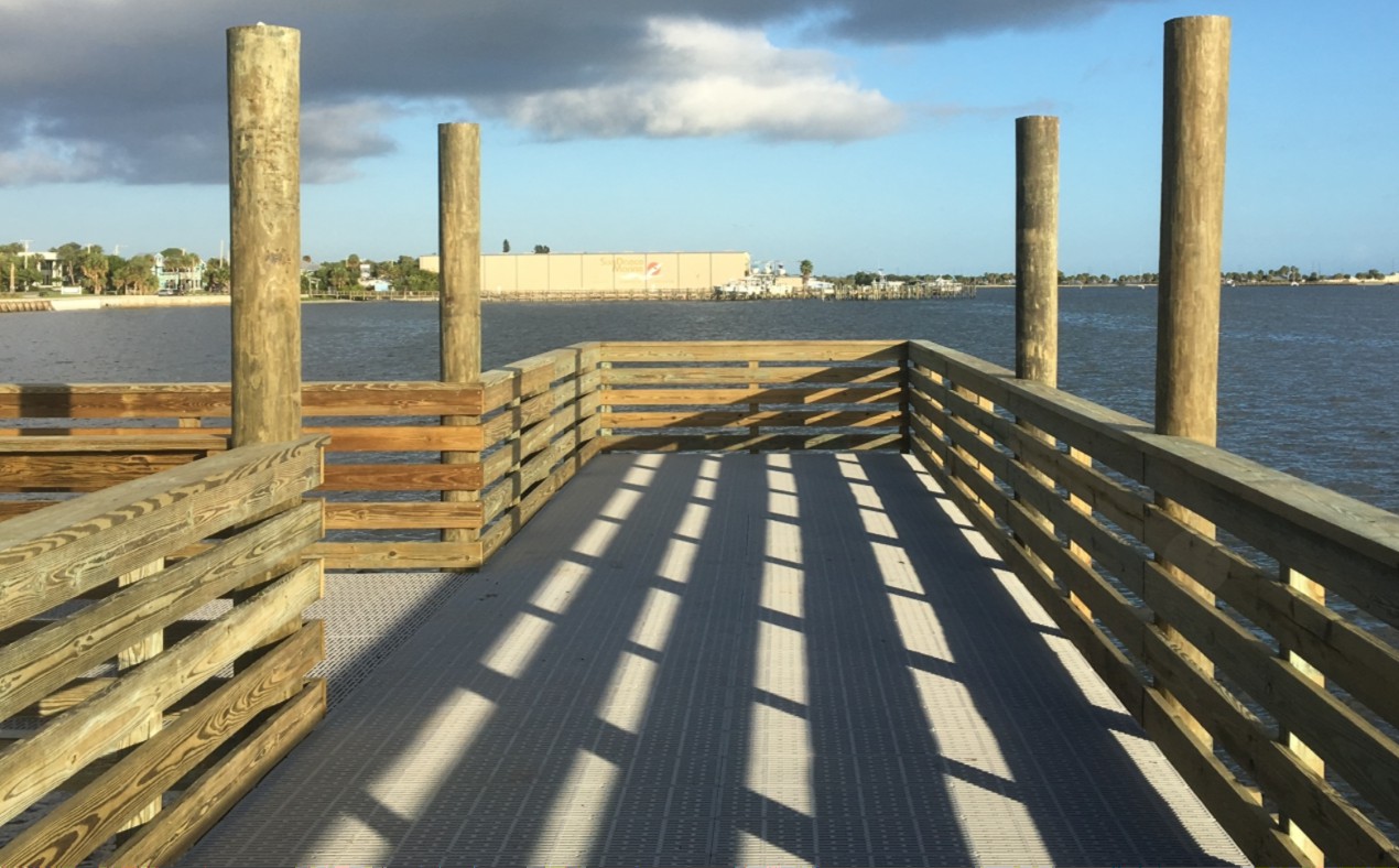 Wooden observation pier with grated decking and pilings overlooking a calm bay