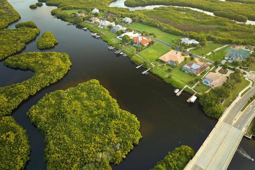 Aerial view of waterfront homes with private docks along a winding mangrove-lined waterway