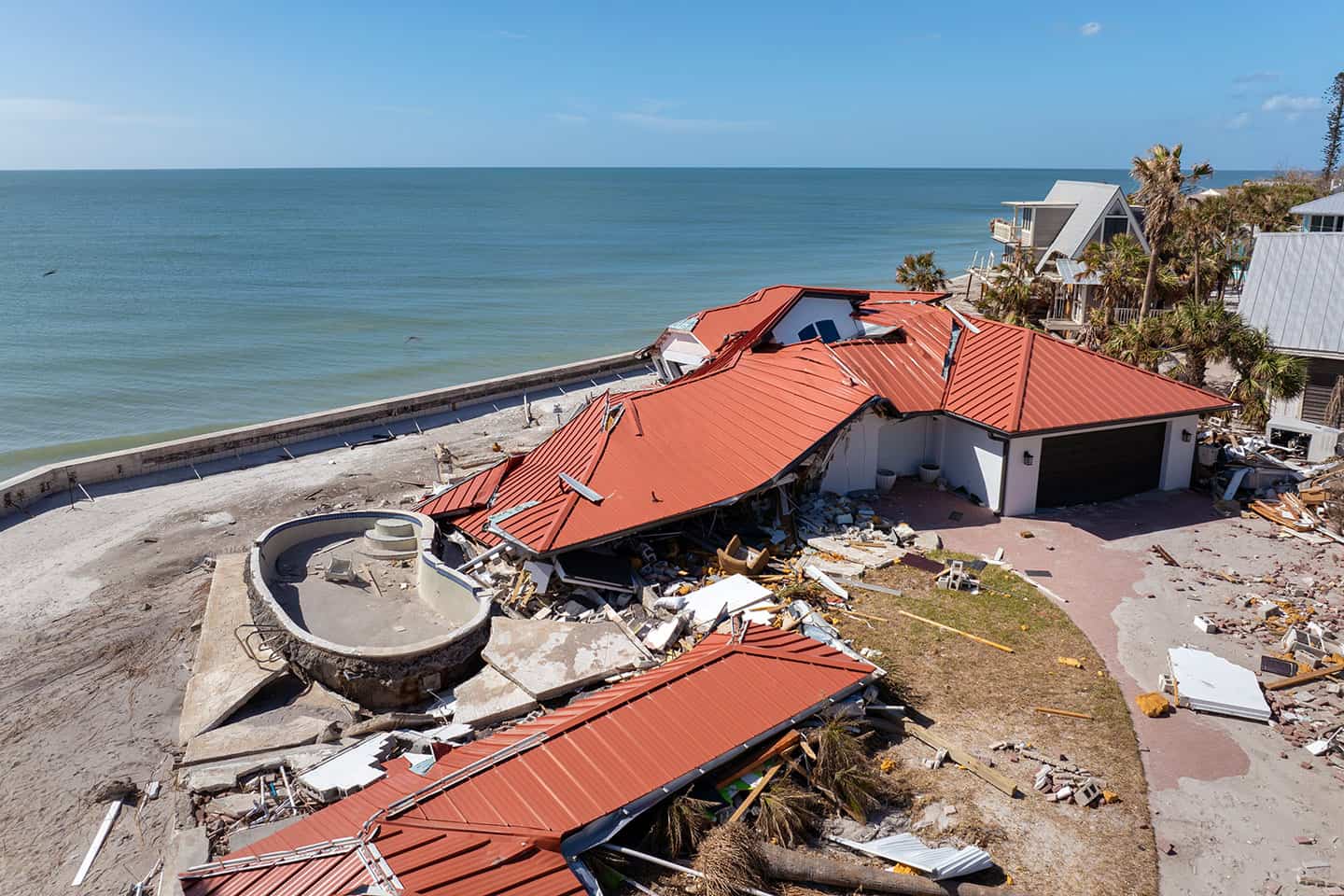Collapsed beachfront home with red roof destroyed by coastal storm surge
