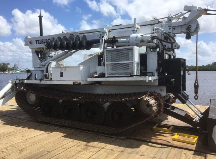 Track-mounted marine construction drill rig with hydraulic equipment on a dock